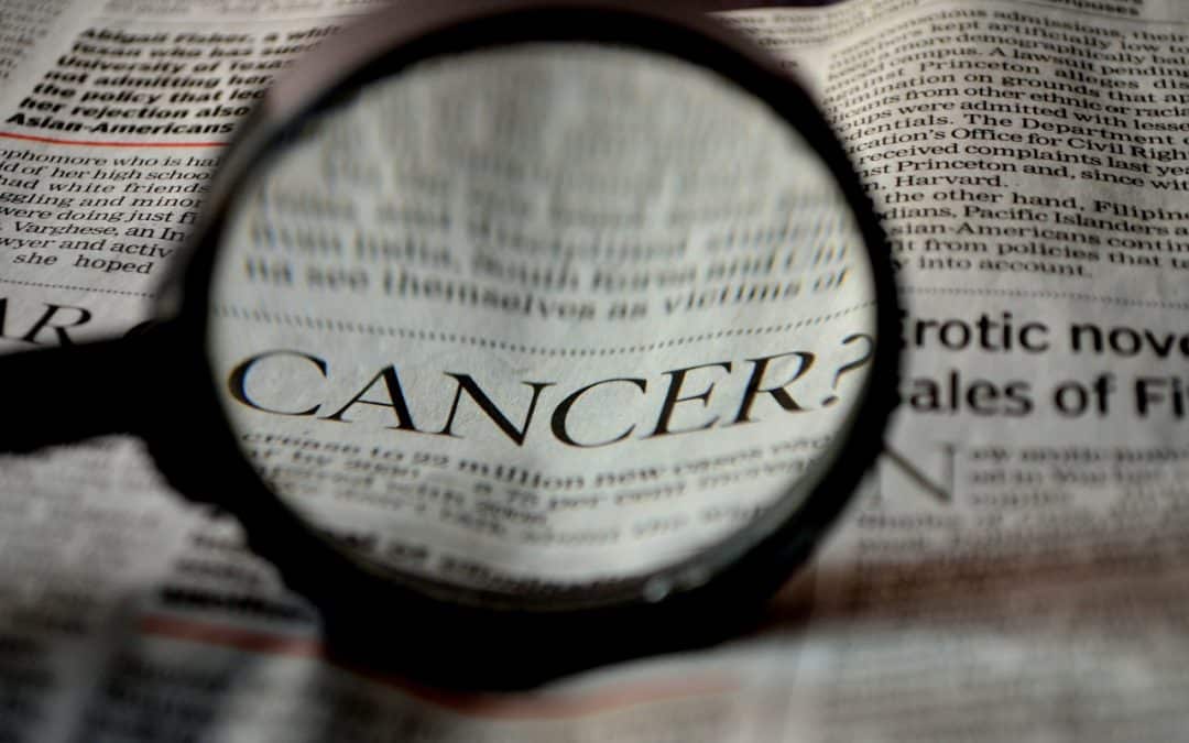 Magnifying glass highlighting Cancer headline on a newspaper
