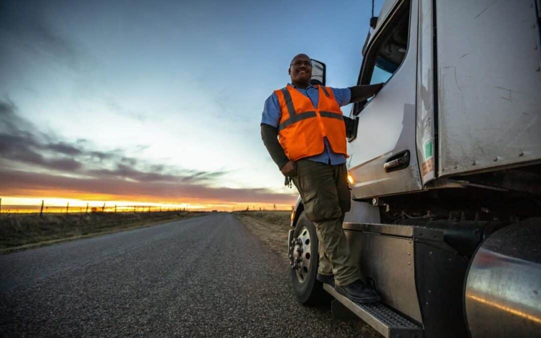 Owner operator truck driver reviewing health insurance options beside semi truck